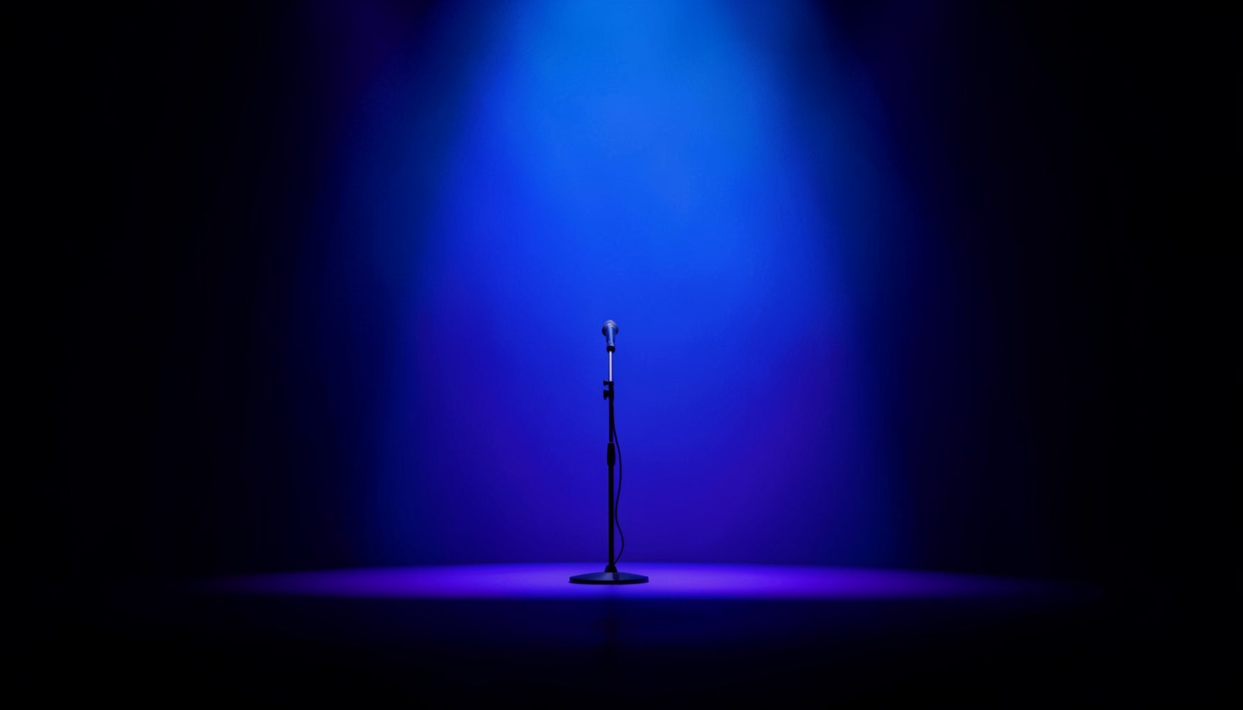 A dark concert hall with deep blue and violet stage lighting washing over an empty stage, a single microphone stand silhouetted against the glow, the atmosphere quiet and expectant.